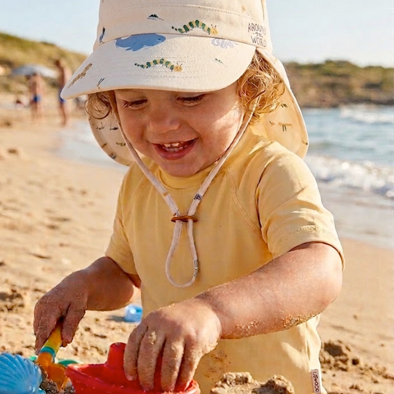 Kleinkind mit Liewood Badehut mit sicherem Kinnband beim Sand spielen